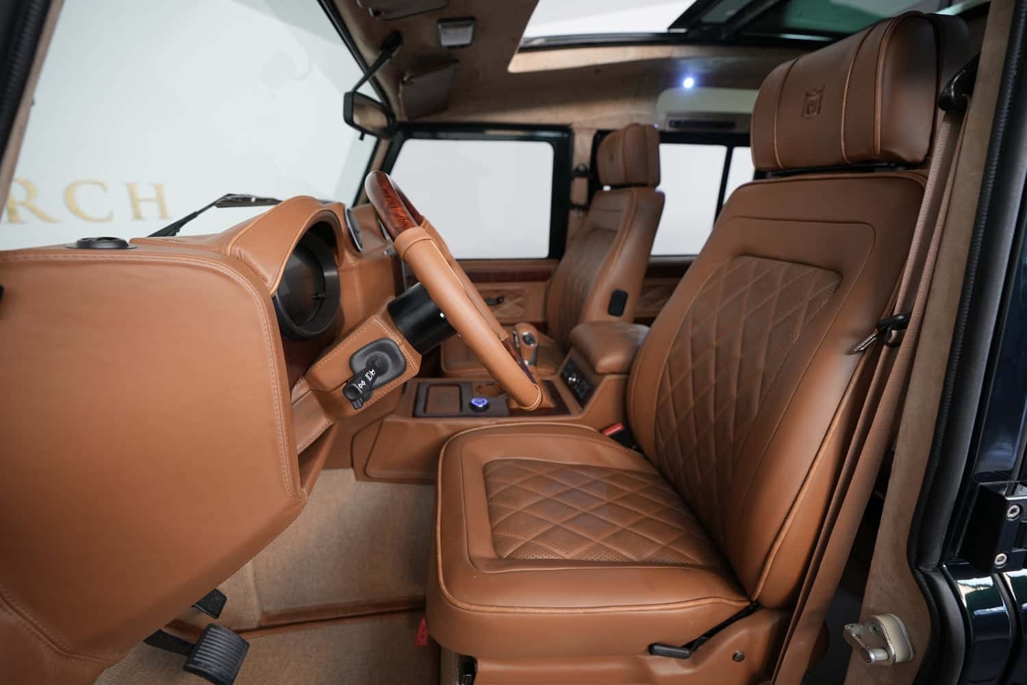 Interior Shot: Luxury Cabin Interior view of a custom Land Rover Defender with premium tan leather upholstery and modern dashboard features