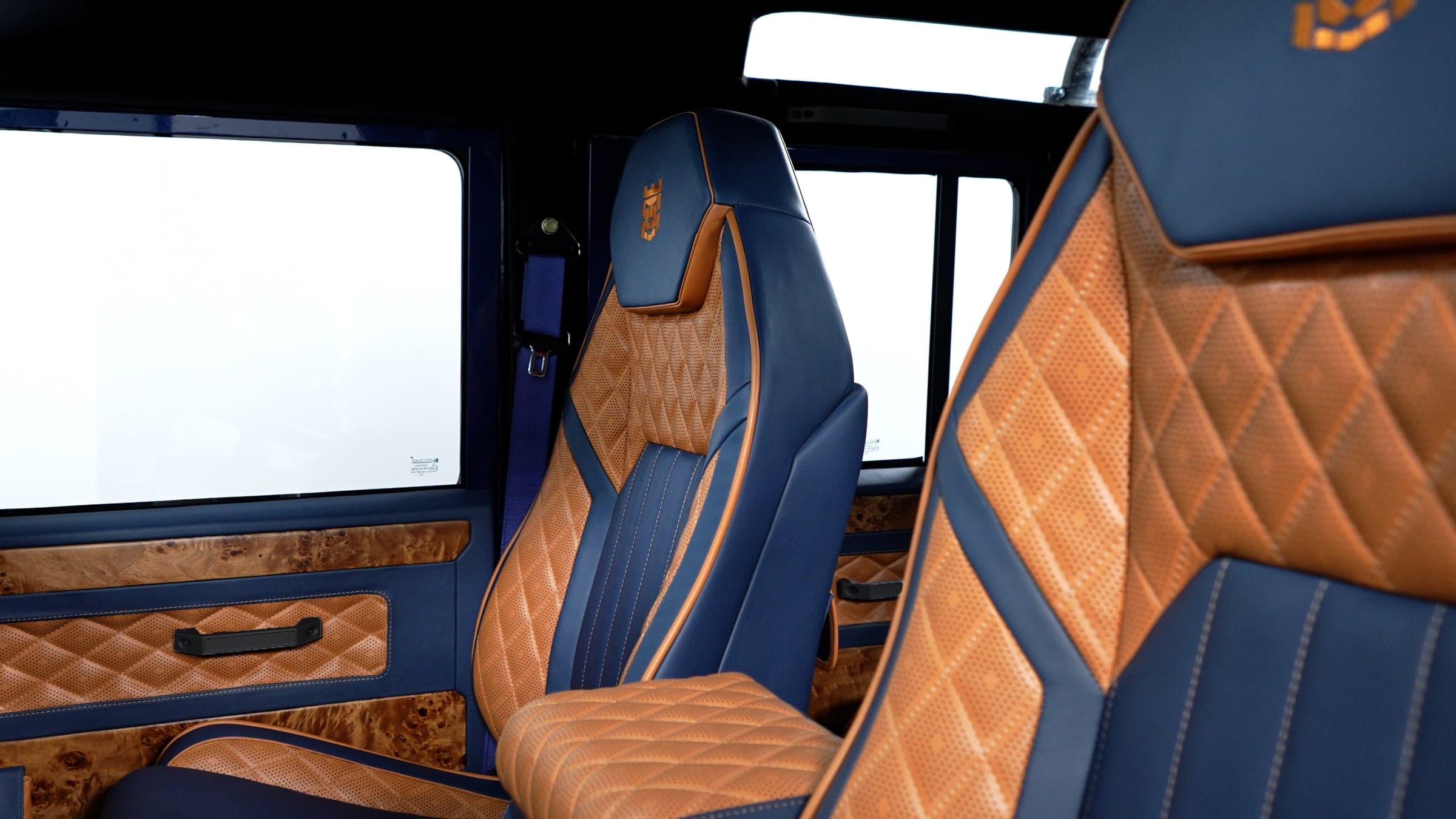 Interior Shot: Bespoke Seating Close-up of custom Land Rover Defender interior featuring luxurious blue and tan diamond-stitched seats