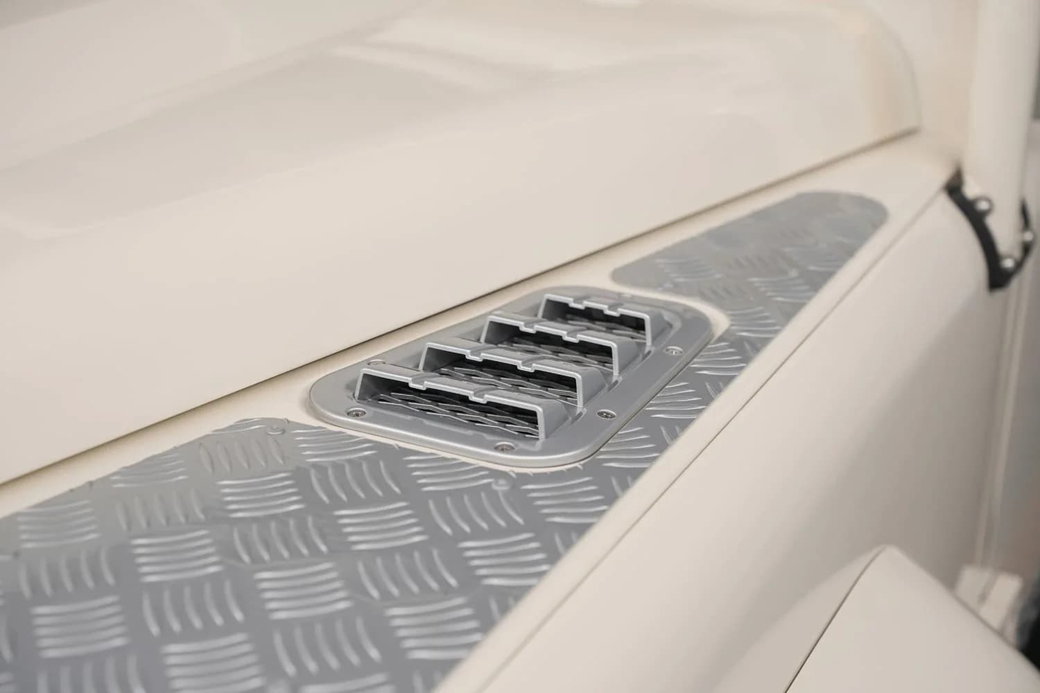 Close-up detail shot of a Defender's aluminum body panel rivets, showing the hand-built craftsmanship, with a galvanized chassis visible underneath