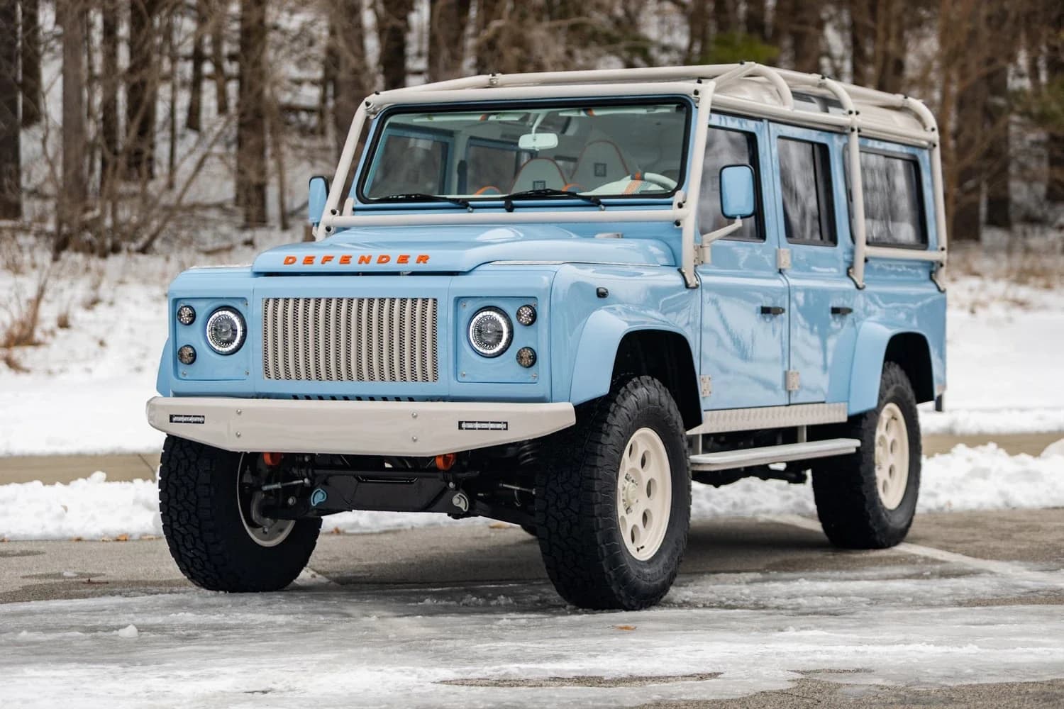 A restored early Series I Land Rover in blue, photographed on a backdrop